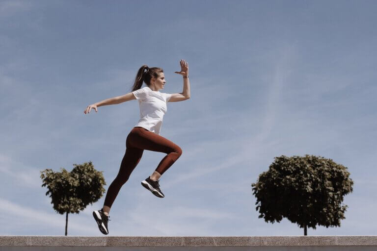 a woman in white shirt and brown leggings running on the street