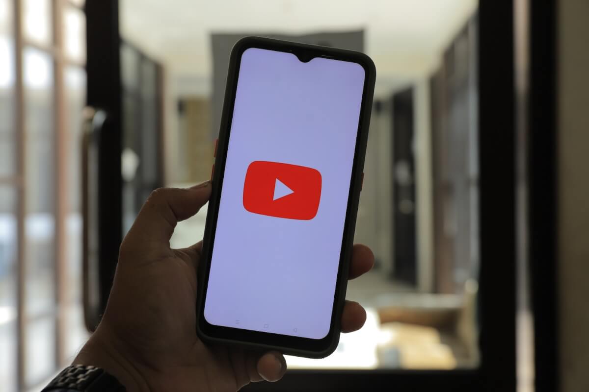Person Holding a Black Cellphone With the YouTube Logo on the Screen