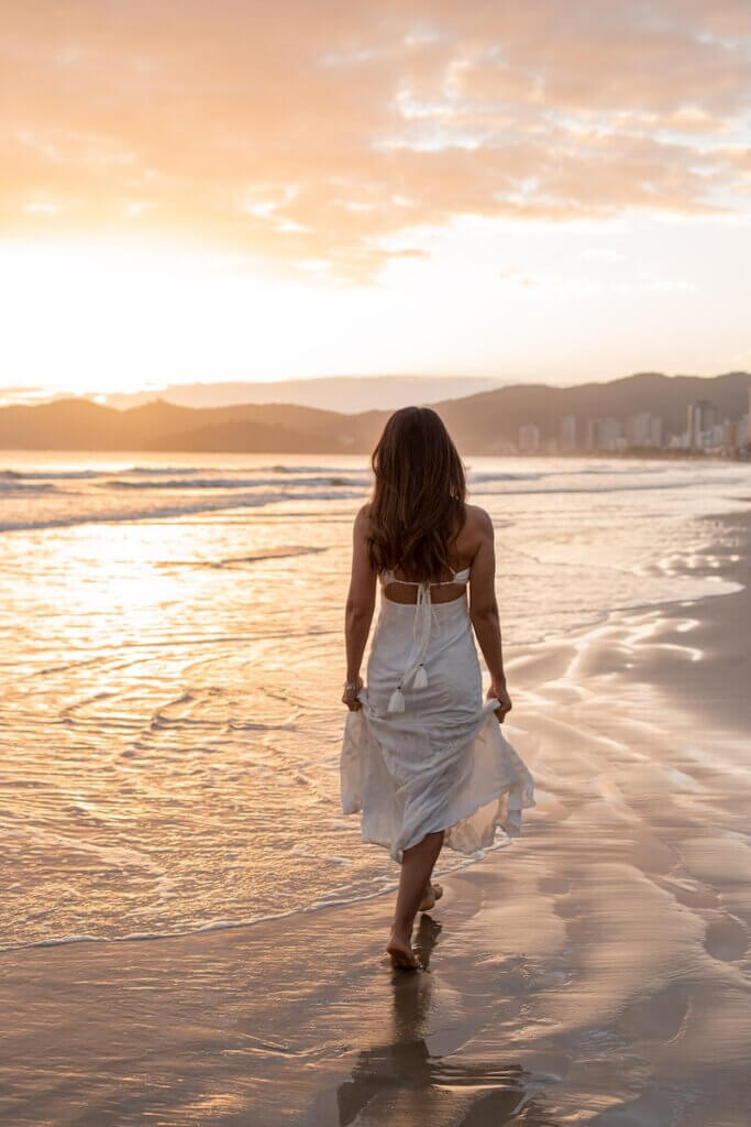 Woman Walking along the Seaside Wearing a White Flowing Dress