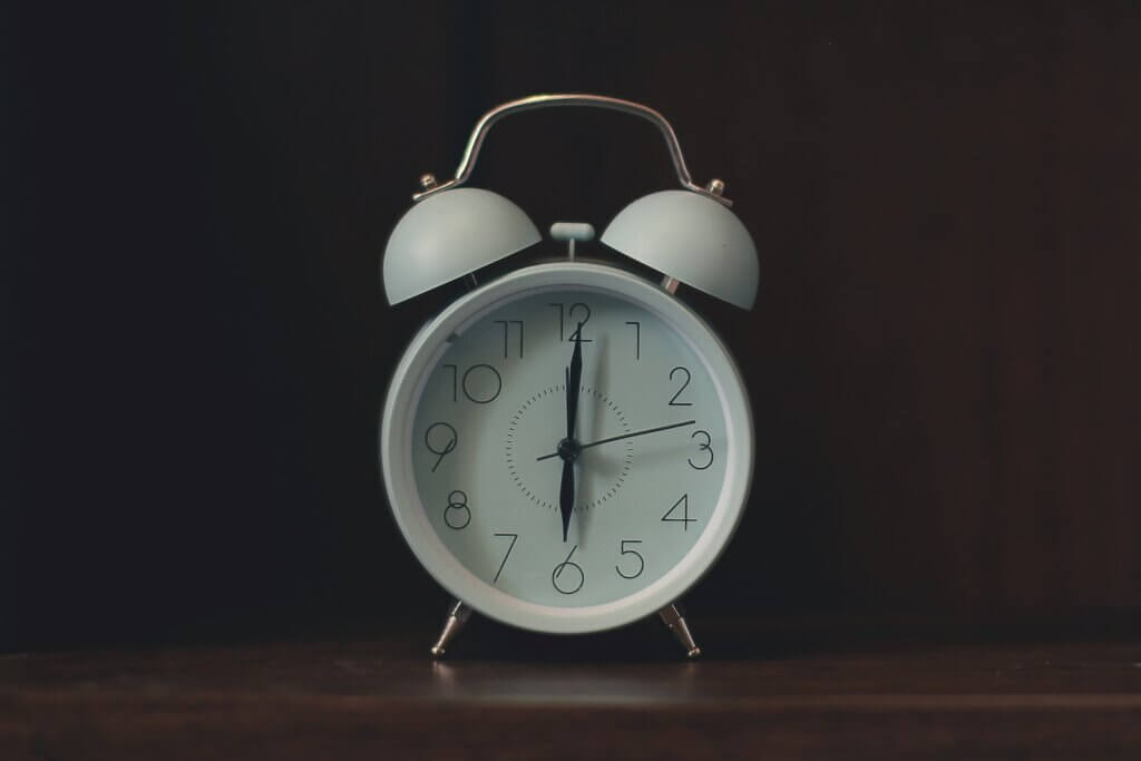 White old-fashioned alarm clock, set to 6 o'clock
