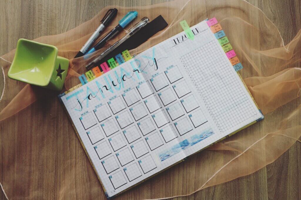 Photo of Planner Book and Writing Materials On Brown Surface
