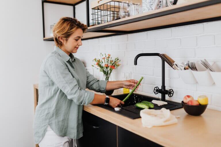 Woman Rinsing Vegetables at Sink in Kitchen