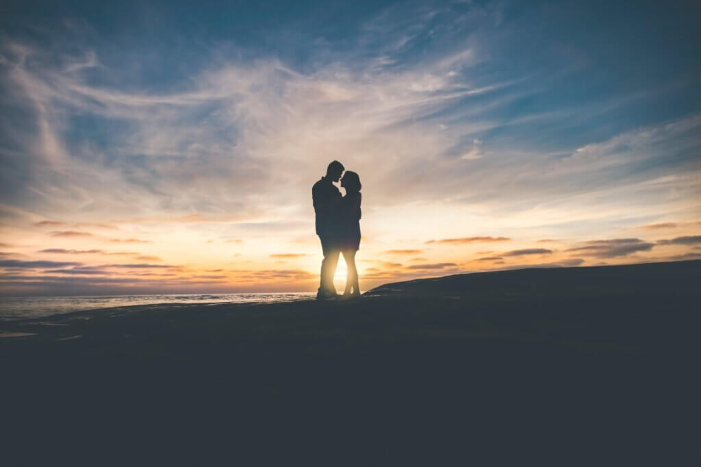 Silhouette of man and woman hugging each other with sunset in background