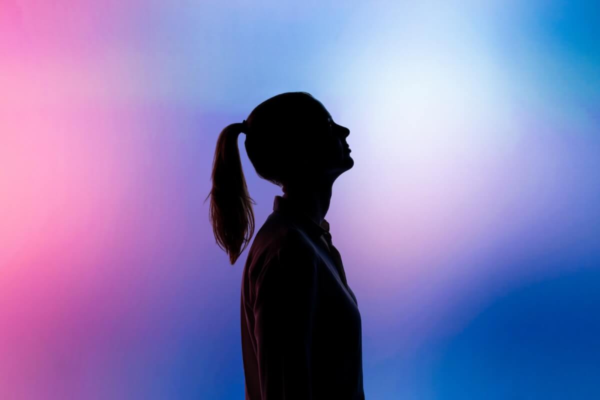Side View Silhouette of Woman With Hair In Ponytail On A Pink and Blue Background