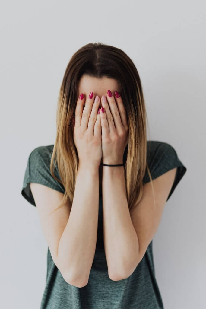 Standing Upset Woman Wearing Gray Short Sleeved Shirt Covering Her Face With Her Hands