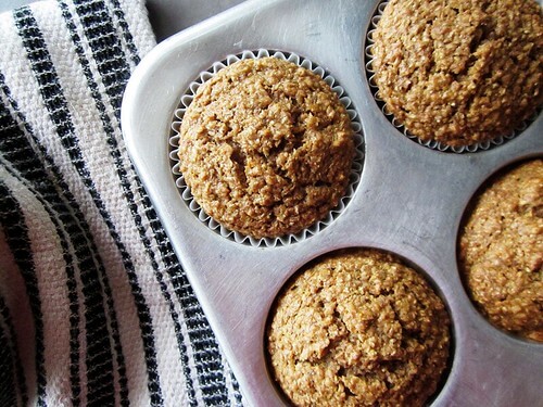 Bran muffins in a metal baking tin sitting atop a blue and white striped towel
